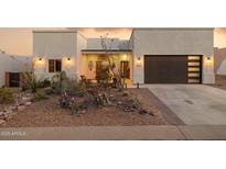 Inviting desert-style home featuring xeriscaping and modern garage door with glass panels at 9827 E Fortuna Ave, Gold Canyon, AZ 85118