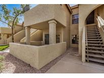 Exterior view of the condo building showing covered entryway with stairs to upper levels and beige stucco at 1126 W Elliot Rd # 1014, Chandler, AZ 85224