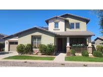 Charming two-story home featuring a welcoming front porch, beautiful landscaping, and a well-manicured lawn at 15418 W Surrey Dr, Surprise, AZ 85379