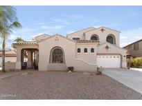 Inviting home exterior with neutral stucco, arched windows, tile roof, two-car garage and rock landscaping at 3557 S Halsted Ct, Chandler, AZ 85286