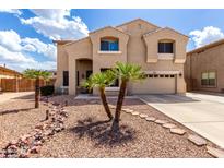 Charming two-story home featuring a well-maintained front yard with desert landscaping and young palm trees at 8341 W Palo Verde Ave, Peoria, AZ 85345