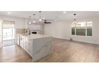 Open-concept kitchen featuring a large island, modern lighting, and a decorative brick fireplace focal point at 10836 N 108Th N Pl, Scottsdale, AZ 85259