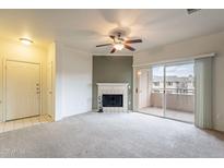 Light-filled living room featuring a fireplace, neutral carpet, and sliding glass doors to balcony at 16013 S Desert Foothills Pkwy # 2055, Phoenix, AZ 85048