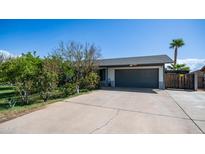 Charming single-story home featuring a gray two-car garage, mature trees, and a concrete driveway at 18829 N 23Rd Ave, Phoenix, AZ 85027