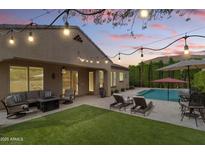 Outdoor backyard oasis features a swimming pool, lounge chairs, patio furniture, string lights, and manicured landscaping at 2664 E Ebony Dr, Chandler, AZ 85286