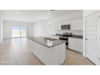 Bright kitchen features white cabinets, a gray granite island, stainless steel appliances, and seamless access to the dining area at 1331 W Hess Ave, Coolidge, AZ 85128