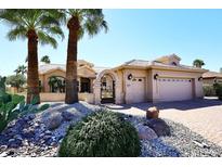 Inviting desert home featuring a gated entrance, mature palm trees, and a three car garage at 15061 W Pinchot Ave, Goodyear, AZ 85395