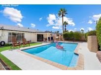 Backyard pool with flamingo float, outdoor seating, and tropical landscaping creates a relaxing oasis at 7502 E Princeton Ave, Scottsdale, AZ 85257
