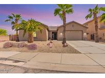 Charming single-story home featuring a two-car garage and desert landscaping with mature palm trees at 13155 W Monterey Way, Litchfield Park, AZ 85340