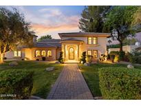 Elegant home exterior with a beautiful walkway, manicured lawn, and warm exterior lighting at dusk at 2106 E La Vieve Ln, Tempe, AZ 85284