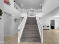 Bright entryway featuring a grand staircase with white railings and tiled floors at 13637 W Port Royale Ln, Surprise, AZ 85379