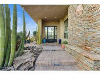 Inviting front entrance with stone accents, desert landscaping, and a modern glass door at 38199 N Tranquil Way, Carefree, AZ 85377