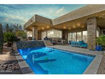 Inviting backyard pool with a stone accent wall and modern outdoor furniture, perfect for relaxation at 38199 N Tranquil Way, Carefree, AZ 85377