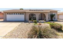 Charming single-story home featuring a well-maintained front yard, a two-car garage, and arched front entryway at 5221 W Garden Dr, Glendale, AZ 85304