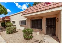 Tan townhome featuring a red tile roof, security bars on windows, and drought-tolerant landscaping at 17242 N 16Th Dr # 6, Phoenix, AZ 85023