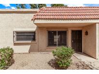 Tan home featuring a red tile roof, security bars on the windows, and low-maintenance landscaping at 17242 N 16Th Dr # 6, Phoenix, AZ 85023