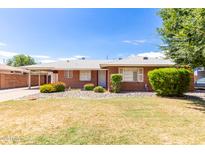 Charming brick home with a well-maintained lawn, rock landscaping, and mature shrubbery under a bright blue sky at 2131 W Verde Ln, Phoenix, AZ 85015