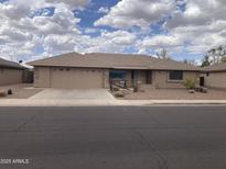 Tan home showcasing a desert landscaped front yard, stone accents, and a two-car garage, under a bright, partly cloudy sky at 2152 S Olivewood --, Mesa, AZ 85209
