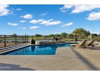 Backyard pool with tiled water feature, stone surround, lounge chairs, and views of a lake at 3842 E Alameda Ln, Gilbert, AZ 85298