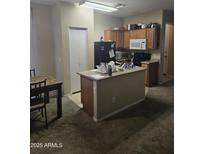 View of a kitchen featuring an island, wooden cabinets, and a refrigerator at 6629 W Polk St, Phoenix, AZ 85043