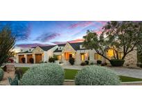 Charming single-story home featuring stone accents, manicured landscaping, and a three-car garage at 8220 E Sharon Dr, Scottsdale, AZ 85260
