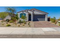 Charming single-story home featuring a gray garage door, brick driveway, and desert landscaping at 11738 S 173Rd Ln, Goodyear, AZ 85338