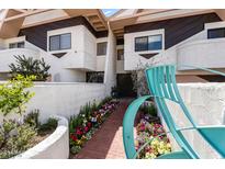 Inviting exterior featuring a quaint brick walkway with vibrant floral landscaping and unique architectural details at 33 W Missouri Ave # 17, Phoenix, AZ 85013