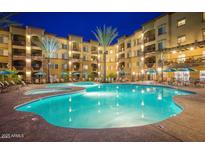 Resort style pool and spa illuminated at night with lounge chairs and umbrellas at 5350 E Deer Valley Dr # 2435, Phoenix, AZ 85054