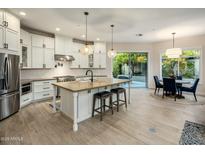 Spacious kitchen with white cabinetry, central island with seating, and stainless steel appliances at 7979 E Princess Dr # 26, Scottsdale, AZ 85255