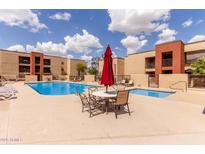 Community pool with table and umbrella and chairs for rest and relaxation near the spa at 1340 N Recker Rd # 109, Mesa, AZ 85205