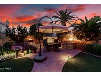 Inviting backyard patio featuring a dining table under an umbrella, lush greenery, and a charming water feature at 1502 W Wagner Dr, Gilbert, AZ 85233