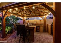 Outdoor kitchen boasts a built-in grill, bar seating, and a mini fridge, perfect for entertaining guests at 1502 W Wagner Dr, Gilbert, AZ 85233