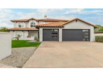Charming two-story home featuring a tiled roof, gray garages, and well-manicured front yard at 10775 N 101St St, Scottsdale, AZ 85260