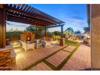 Beautiful outdoor living space with fireplace, pergola, seating, and manicured lawn at 6887 E Hacienda La Colorada Dr, Gold Canyon, AZ 85118