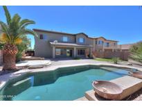 Enjoy the backyard pool and patio with a view of the two-story home's exterior at 44254 W Adobe Cir, Maricopa, AZ 85139