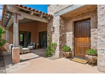 Inviting front entrance featuring a stone facade, covered patio, and a solid wood door with a Welcome mat at 7701 E Golden Eagle Cir, Gold Canyon, AZ 85118