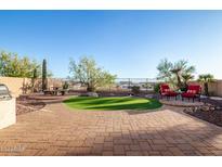 Landscaped backyard features a well-manicured lawn, brick patio, and seating area, perfect for outdoor relaxation and entertaining at 18033 W Tecoma Rd, Goodyear, AZ 85338