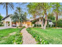 Charming single-story home featuring a brick walkway and beautifully landscaped front yard with mature trees and blooming flowers at 4420 N 47Th Pl, Phoenix, AZ 85018