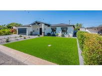 Charming single-story home boasts a lush green lawn and modern desert landscaping at 3010 E Glenrosa Ave, Phoenix, AZ 85016