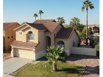 Charming beige home with a tile roof, complemented by palm trees and a well-manicured lawn at 1282 W Kesler Ln, Chandler, AZ 85224