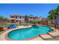 Inviting backyard pool with lounge chairs, picnic table, and lush landscaping, perfect for outdoor entertaining at 12825 W Virginia Ave, Avondale, AZ 85392