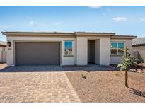 Charming single-story home featuring a gray garage door and desert landscaping at 18147 W Tanglewood Dr, Goodyear, AZ 85338
