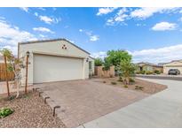 Single-story home with two-car garage featuring a brick driveway and desert landscaping at 5312 W Hardtack Trl, Laveen, AZ 85339
