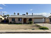 Modest one-story home with attached garage and minimal landscaping under a blue sky at 7961 W Campbell Ave, Phoenix, AZ 85033