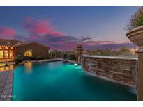 Stunning pool featuring a rock waterfall, lush landscaping, and beautiful desert views in the background at 1607 W Pearce Rd, Phoenix, AZ 85041