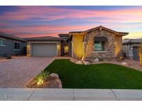 Charming home exterior featuring a stone facade, well-manicured lawn, and a paved driveway at 32268 N 133Rd Ln, Peoria, AZ 85383