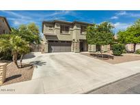 Two-story home featuring desert landscaping, a wide driveway, and neutral-tone exterior at 44566 W High Desert Trl, Maricopa, AZ 85139