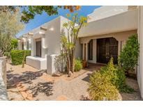 Inviting front entrance with a custom wood door and a well-landscaped courtyard with mature desert landscaping at 7921 N 54Th St, Paradise Valley, AZ 85253