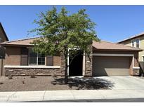 Beautiful single-story home featuring stone accents, a two-car garage, and well-maintained landscaping at 1702 N 214Th Ln, Buckeye, AZ 85396
