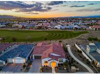 Stunning aerial view of the home with red tile roof, golf course, and mountain views at sunset at 17396 W Crawfordsville Dr, Surprise, AZ 85388